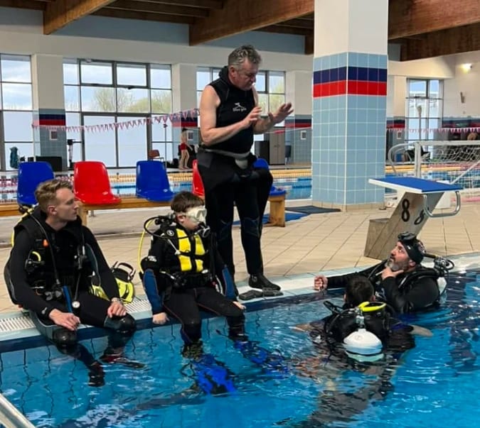 Cosmin Brinzeanu explică un exercițiu cursanților, la marginea piscinei